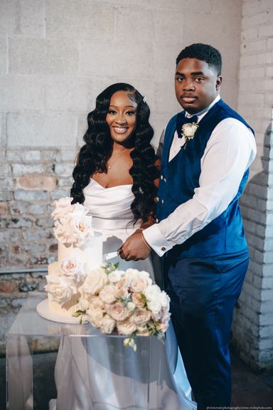 Bride and Groom pose behind their cake